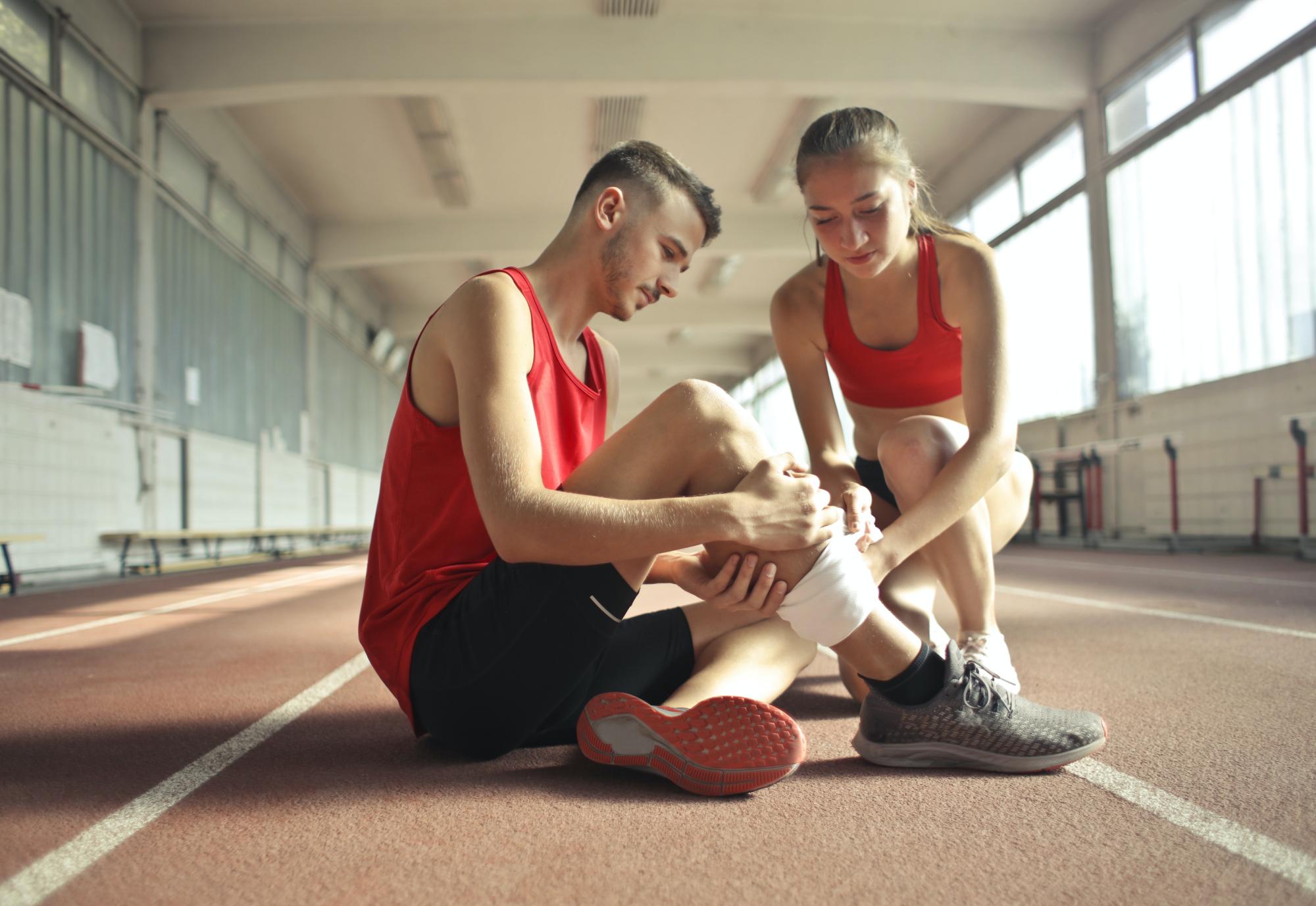 Een sporter krijgt een verband om zijn knie